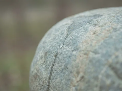 A close view of water moving over stone, showing a thin rivulet catching the light.